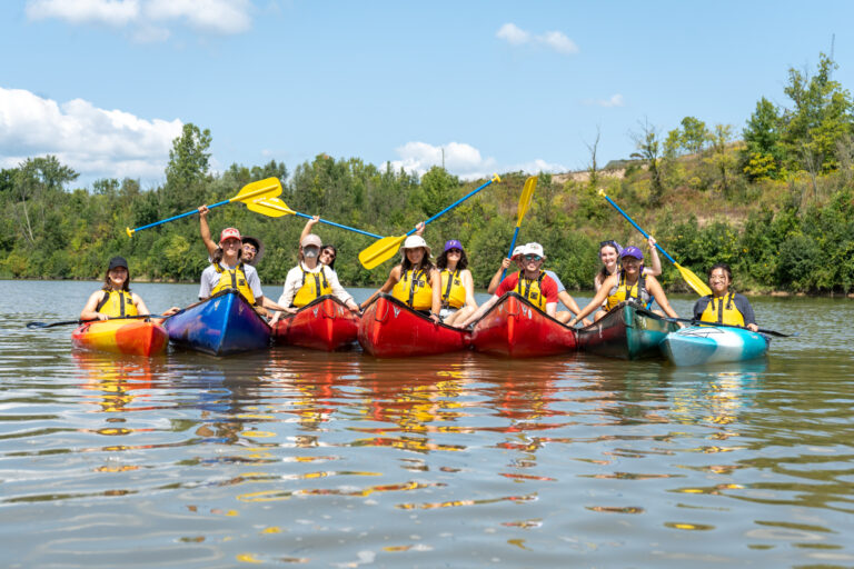 First year students sitting in canoes enjoying rafting on the lake.