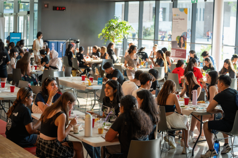 First-year students sitting at tables talking and laughing.