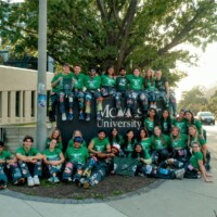 Large group of Faculty Representatives posing in front of a sign that says 'McMaster University'.