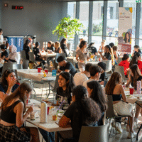 First-year students sitting at tables talking and laughing.