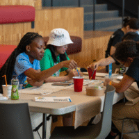 First-year students sitting at a table painting.