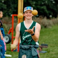Faculty Representative smiling and juggling three yellow balls.