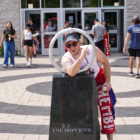 A faculty representative posing with a statue labelled 'THE IRON RING'.