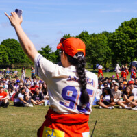 A group of first-year students sitting on the grass listening to a Faculty Representative.