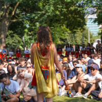 First year students sitting on the grass listening to the Engineering mascot.
