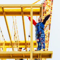 Faculty representative smiling in a harness on top of a climbing tower.
