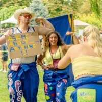 Faculty reps flexing their biceps holding a sign saying ' ASK ME ABOUT ANYTHING!!!'.