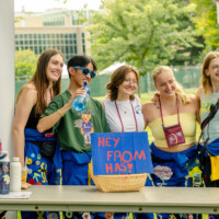 Faculty representatives standing in front of a booth that has a sign saying 'Hey FROM HAS!'.