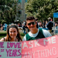 Representatives holding signs that say 'WE LOVE 1st YEARS' and ' ASK ME ANYTHING'.