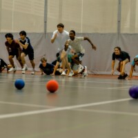 First-year students running for dodgeballs in a gym.