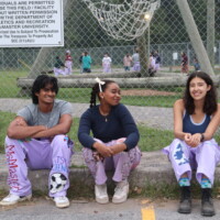 Faculty representatives sitting on a curb smiling in front of the Alpine Tower.