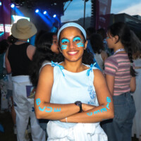 Faculty Representative posing in front of MSU stage wearing paint that says 'BLEED BLUE' on their arms.