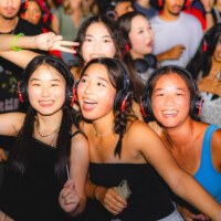First-year students wearing headphones, smiling at the headphone disco event.