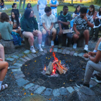 First-year students sitting around a campfire in a circle, talking.