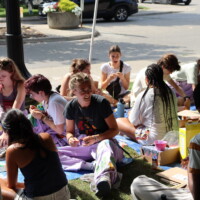 Faculty representatives and first-year students laughing together and making bracelets.
