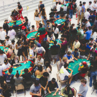 Large shot of multiple poker tables where first-years and Faculty representatives are playing.