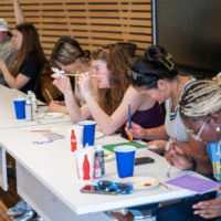 First-year students painting at a table.