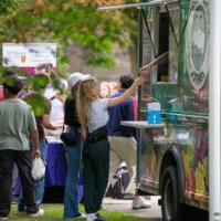First-year student receiving a smoothie from a food truck labelled 'smoothies'.