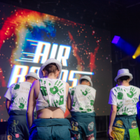 Representatives on a stage with their backs facing the camera in front of a stage projector that says 'AIRBANDS'.