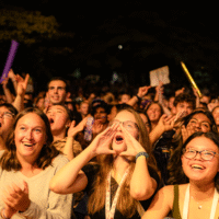 First-year students clapping and cheering at a performance on stage.