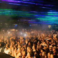 Students singing and jumping at McMaster MSU concert with laser lights above.