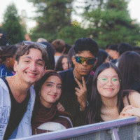 First-years smiling for the camera in front of the stage barricade.